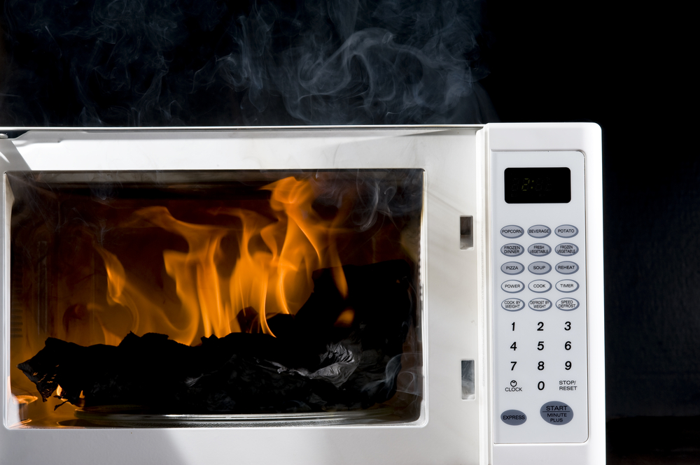 Burnt item on fire inside a white microwave